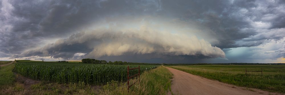 Dark Supercell storm clouds over a rural corn field and dirt road, under a stormy sky, Weather, Environmental Issues, Storm Chasing, Waterville, Kansas, USA.