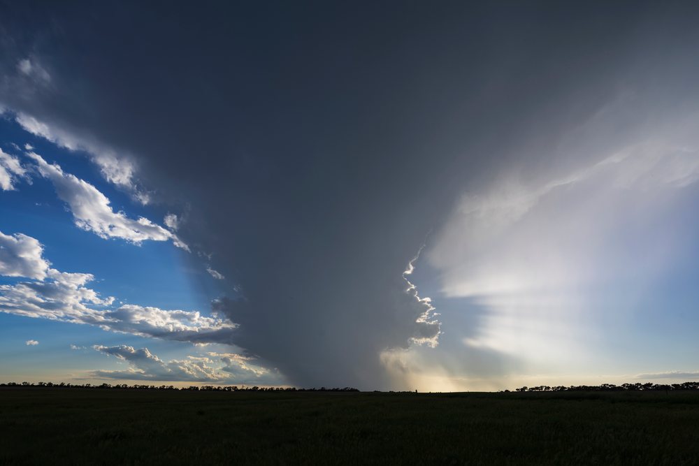 Storm with dark clouds and sunlight over flat field, Storm Chasing, Weather, Environmental, Pukwana, South Dakota, USA.