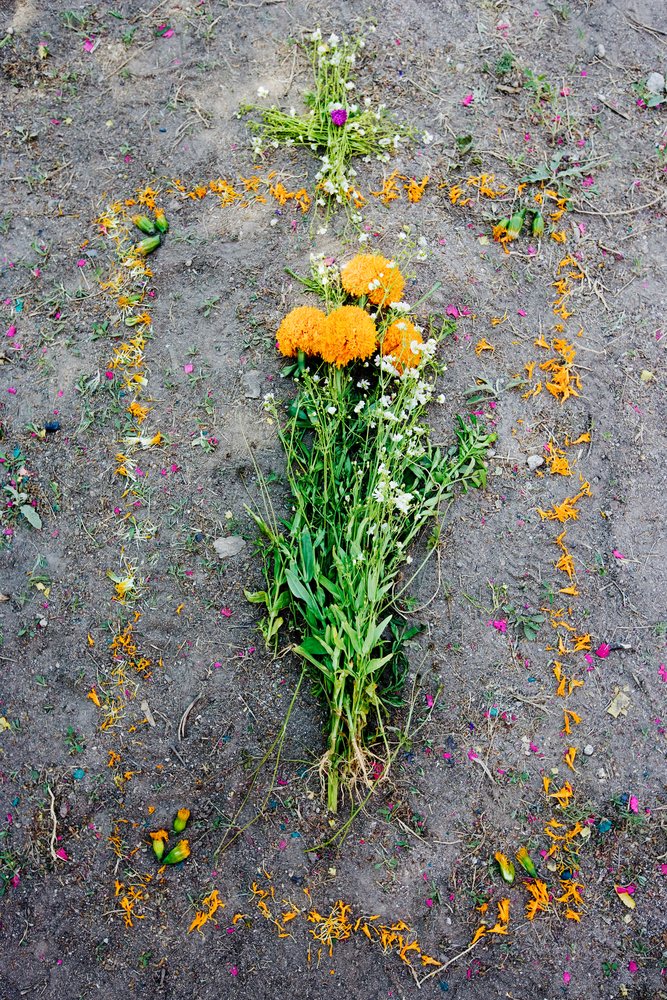 Flowers including orange marigolds and white blooms arranged in a cross and bouquet on a grave site, San Miguel de Allende, Mexico.