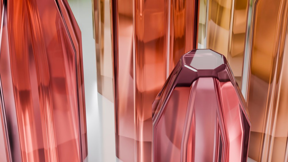 Abstract modern glass sculptures with reflective orange and red tones arranged in a studio environment.