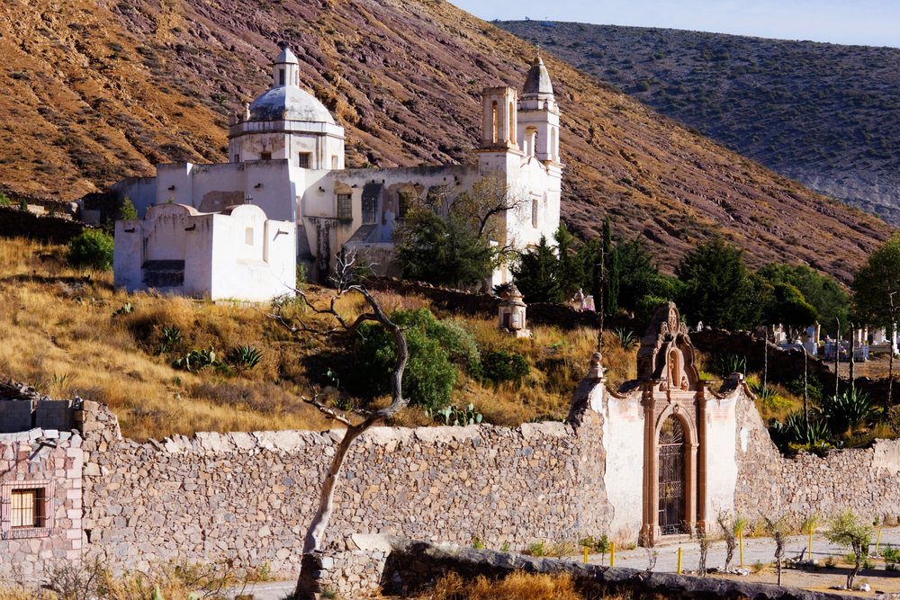 Church of Nuestra Senora de Guadalupe stands on a dry hillside behind a stone wall, San Luis Potosi, Mexico.