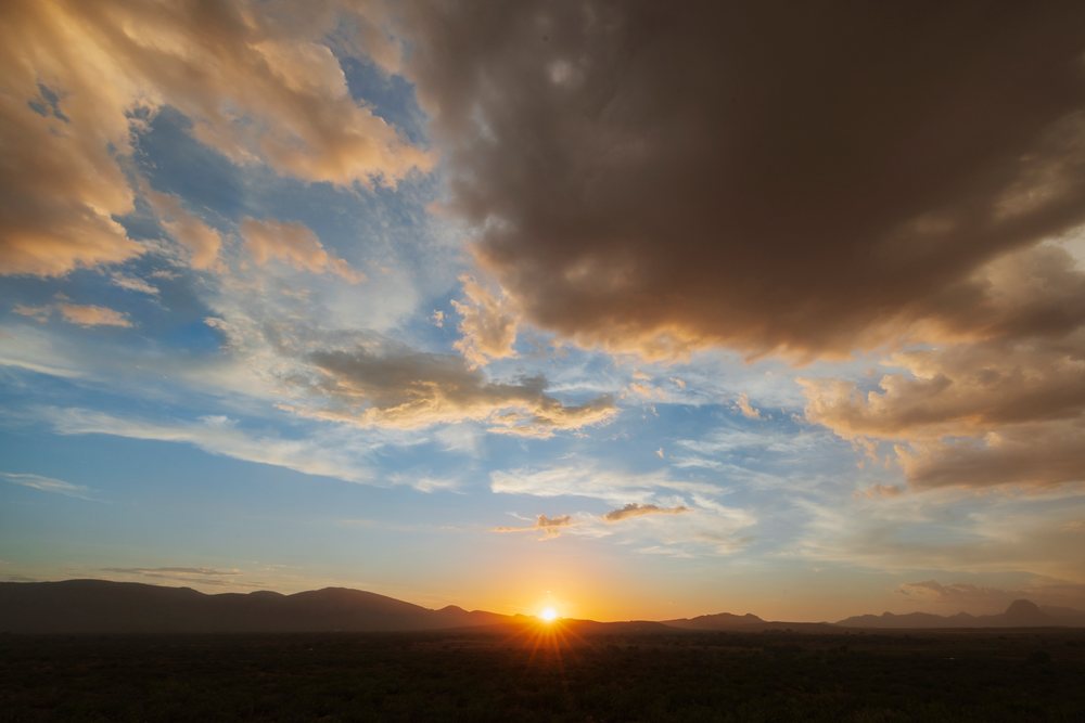 Sun setting over the Dragoon Mountains with dramatic clouds and blue sky, Storm Chasing, Weather, Environmental Issues, Douglas, Arizona, USA.