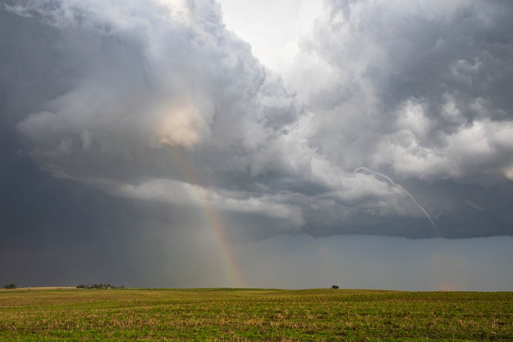 Small Rope Tornado forms beneath storm clouds with a Double Rainbow over a Great Plains field, Dickens, Nebraska, USA.