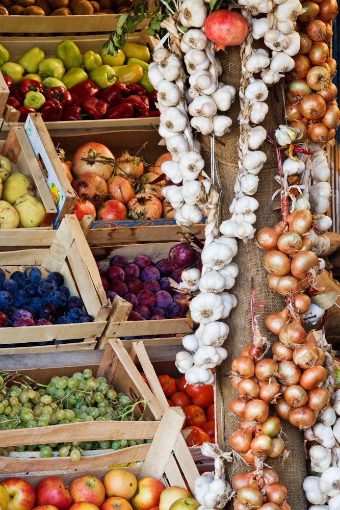 Fruit stand with fresh garlic and assorted fruits and vegetables.