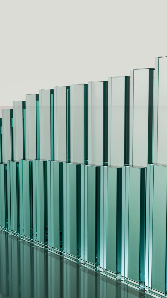 Vertical rectangular glass bars with a blue-green tint arranged in a symmetrical linear pattern on a reflective surface.
