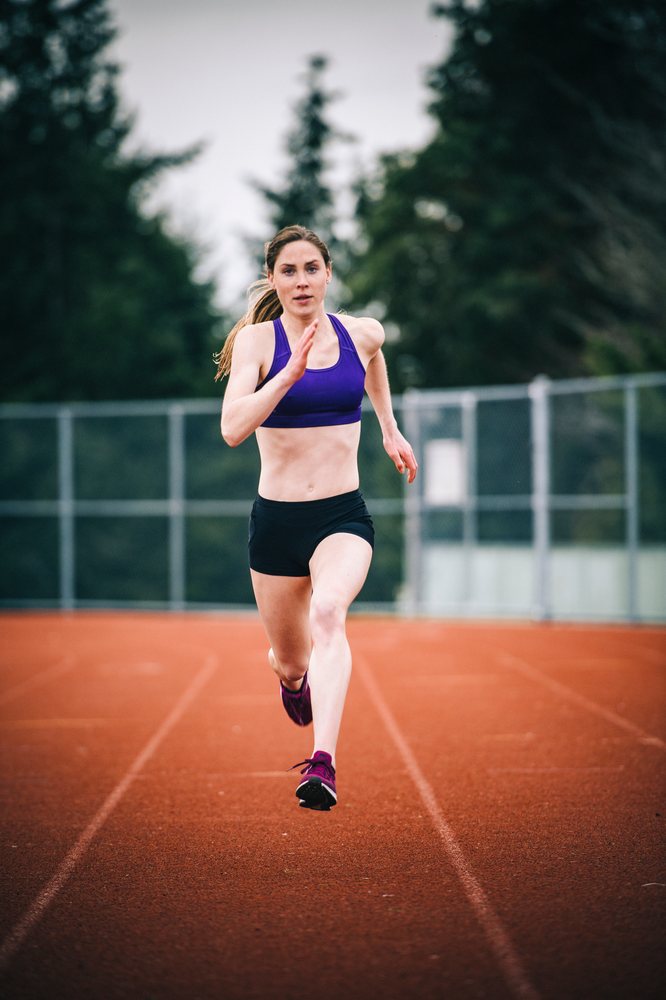 Woman sprinting on an outdoor running track at a USA sports facility during training.