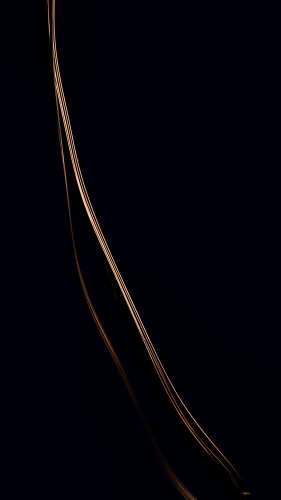 Curved streak of orange light captured in long exposure against a dark background creating an abstract glowing wave effect.