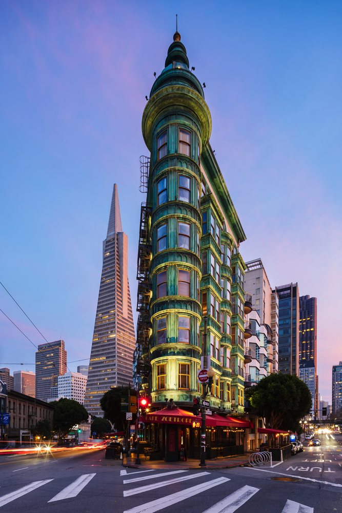 Cafe Zoetrope building stands at the corner of Kearny and Columbus Streets with the Transamerica Pyramid visible behind at dusk, City, Cityscapes, City Life, San Francisco, California, USA.