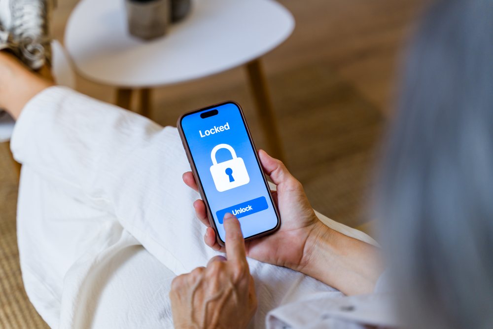 Woman's hand unlocks smartphone on locked screen in casual indoor setting with white table present, Spain.