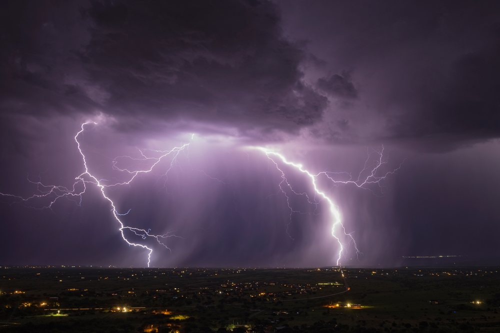 Lightning bolts strike from dark storm clouds over the Sierra Vista landscape at night, Storm Chasing, Weather, Environmental Issues, Arizona, USA.