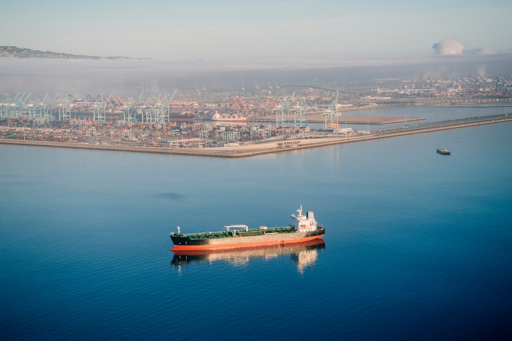Cargo ship anchored in the ocean near container cranes and port infrastructure at the port in Long Beach, lifornia, port in Long Beach, CA, USA.