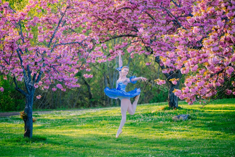 A ballet dancer leaps gracefully outdoors