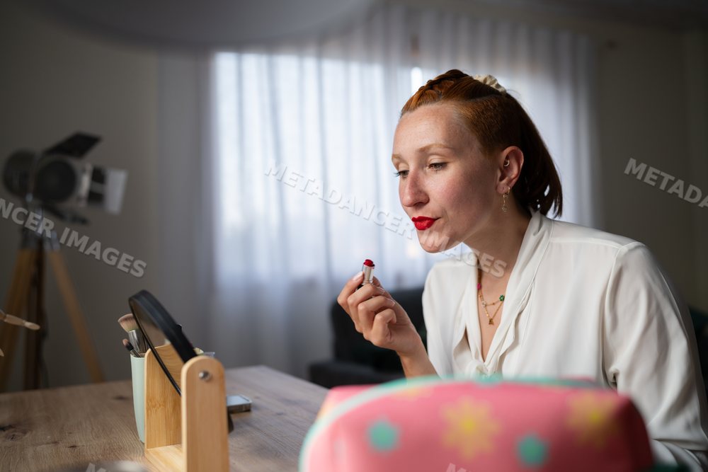A white woman applying red lipstick at home in Galicia, Spain