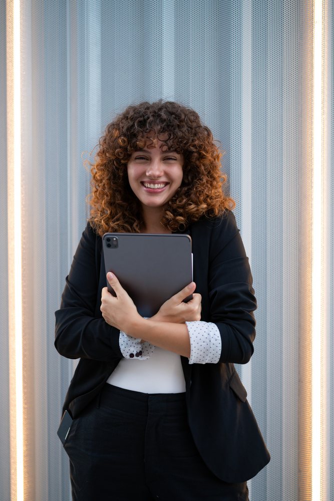 Young woman smiling while holding a tablet indoors, Madrid.