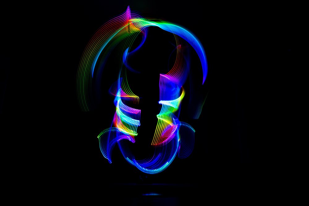 Abstract colorful light painting featuring glowing curved lines in multiple colors on a dark background.