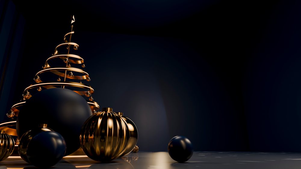 Metal spiral Christmas tree decorated with gold and black ornaments on a reflective floor in a dark interior.
