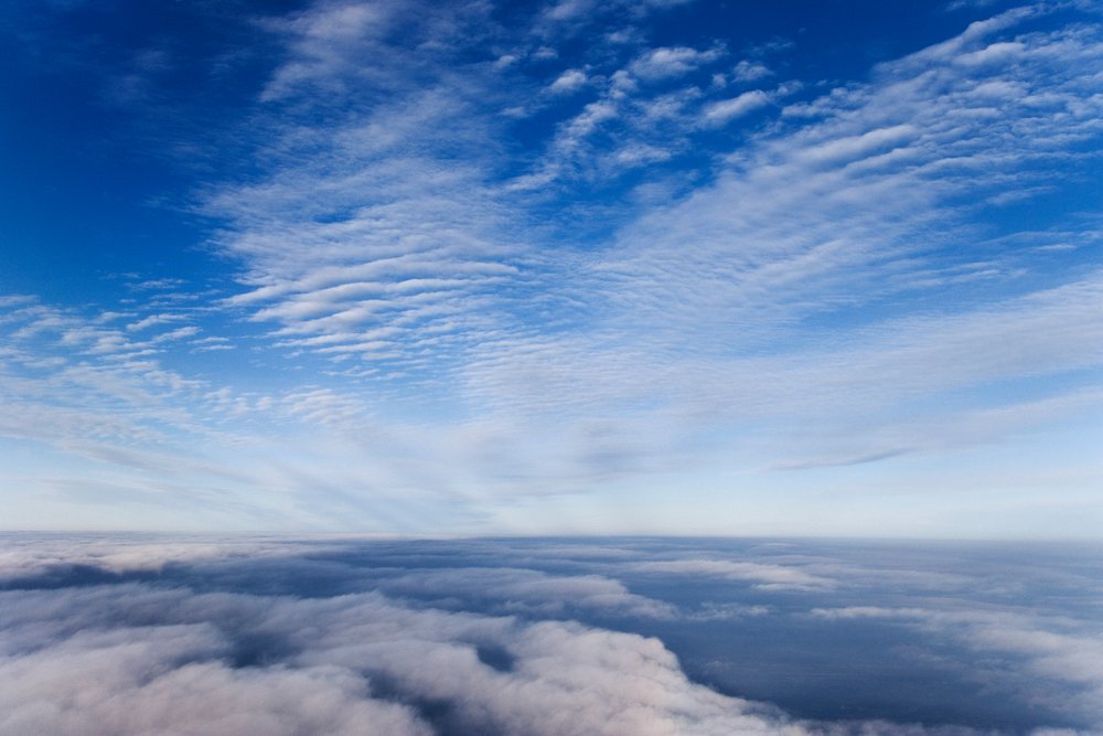 Aerial daylight view of layered fluffy clouds and blue sky from an airplane flying over Japan during winter, Asia.