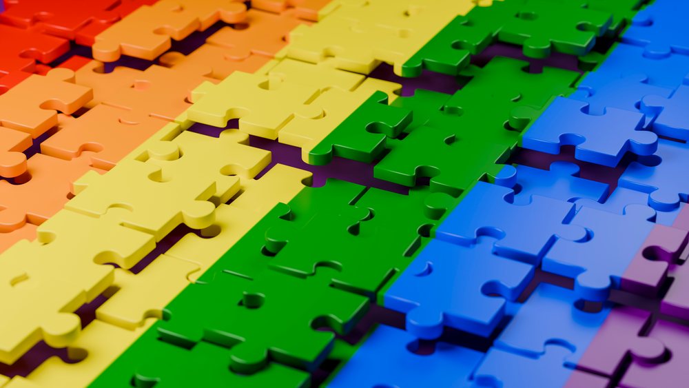 Colorful plastic jigsaw puzzle pieces arranged closely in a flat spectrum layout without visible people.