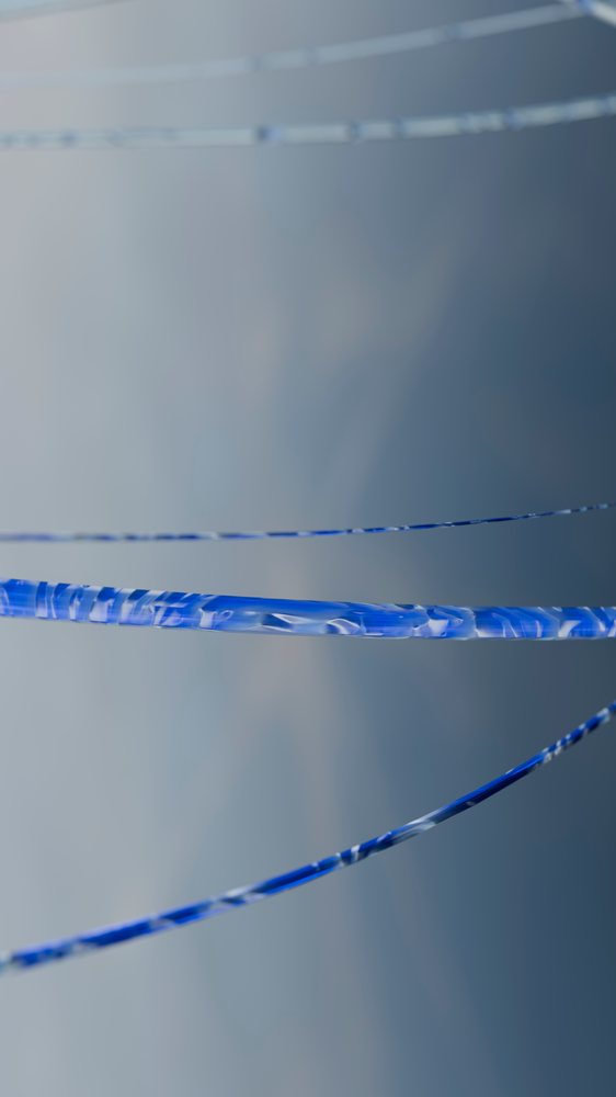 Transparent blue glass threads twisting against a soft focused gray gradient background.