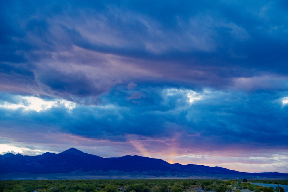 Mountains with a colorful sunset sky, heavy clouds, and sun rays over Nevada desert landscape, USA.