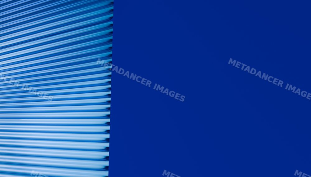Blue metal roller shutter door with horizontal ridges and solid wall
