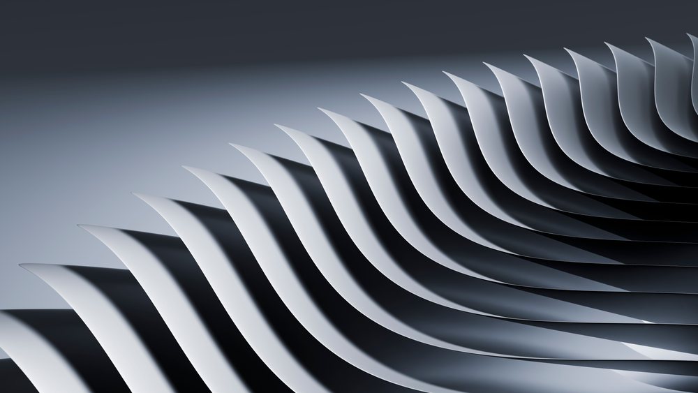 Curved paper shapes arranged in a rhythmic monochrome wave pattern under studio lighting.