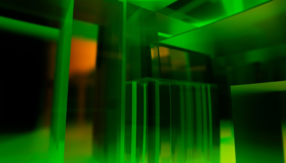 Green translucent glass blocks with geometric shapes and reflections in abstract architectural design.