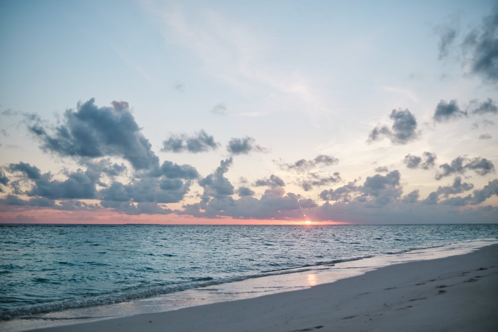 Sunset over the ocean with clouds and a sandy beach in a beach