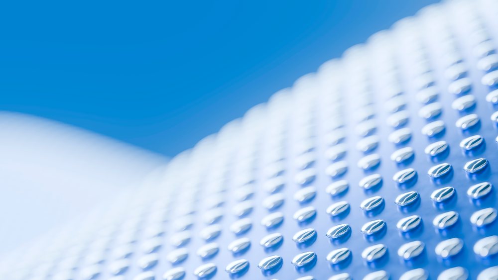 Closeup of a metal surface with rows of raised oval shapes reflecting blue light in a modern industrial pattern.