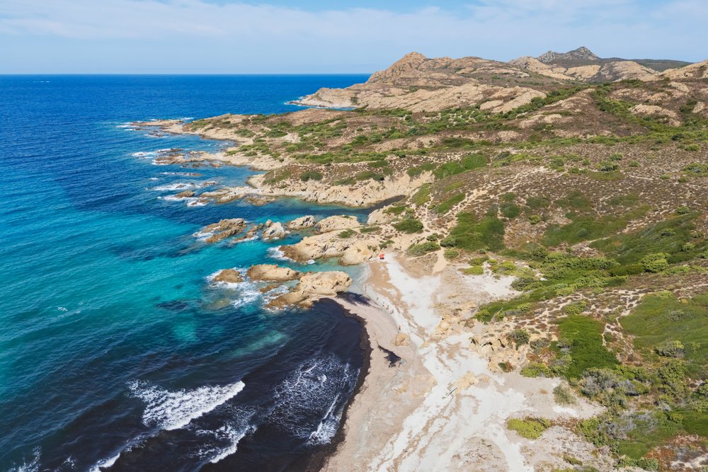 Rocky coastline with waves and blue Mediterranean sea at Plage de l'Ostriconi on a sunny day, Travel Photography, Ile Rousse, Corsica, France.