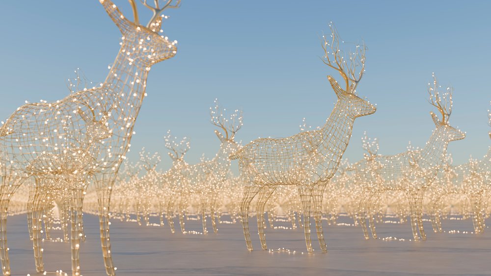 Wireframe reindeer sculptures decorated with glowing holiday lights in an outdoor setting under a clear blue sky.