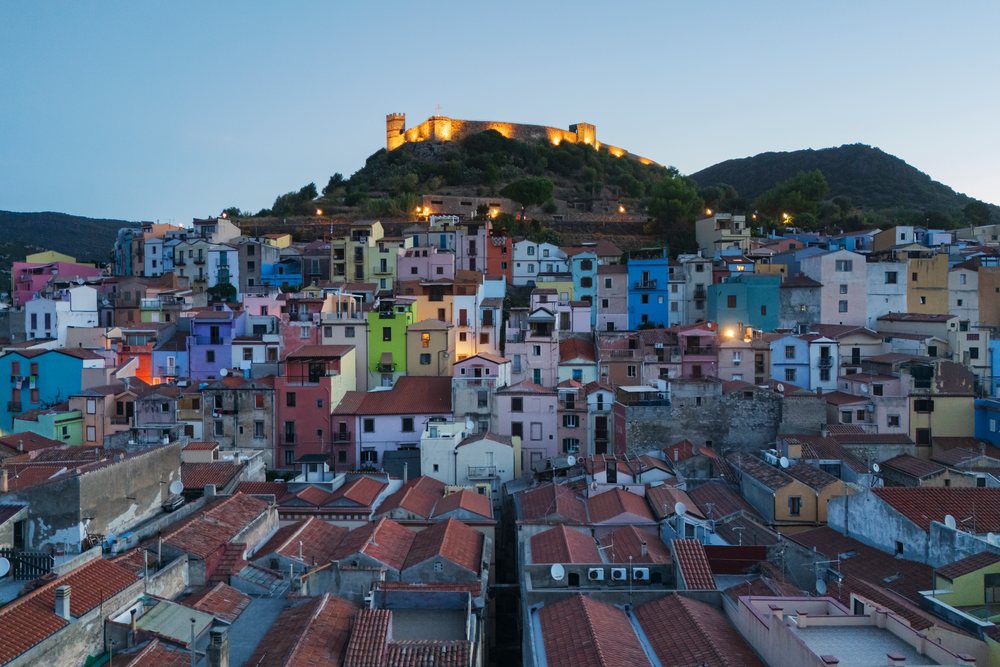 Twilight view of Bosa's old town with colorful buildings and the illuminated Castellodei Malaspina castle on a hill, Travel Images, Sardinia, Italy.