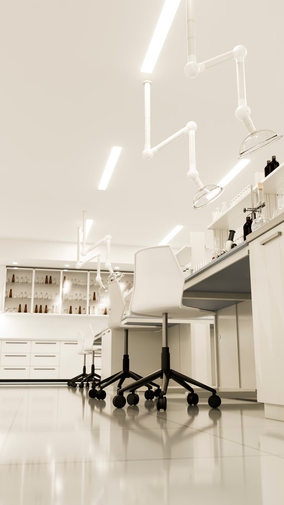 Modern laboratory interior featuring white rolling chairs, work benches with cabinetry, and scientific glassware on counters and shelves under bright lighting.