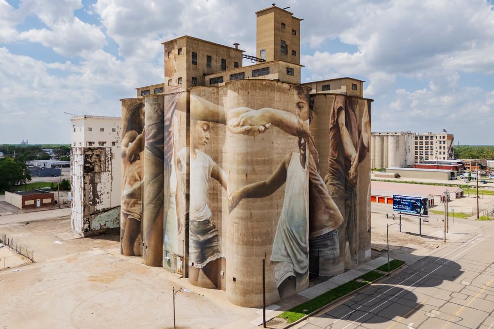 Mural of children holding hands painted on a grain silo, Kansas under a partly cloudy sky, Storm Chasing, Weather, Environmental Issues, Salina, USA.