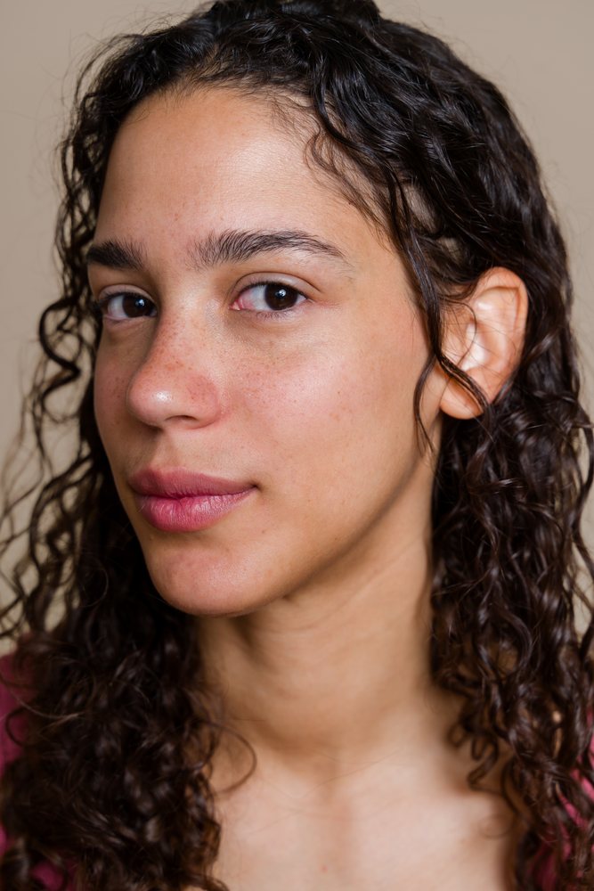 Close-up portrait of a woman with curly hair and freckles in a beauty shoot studio, Spain.