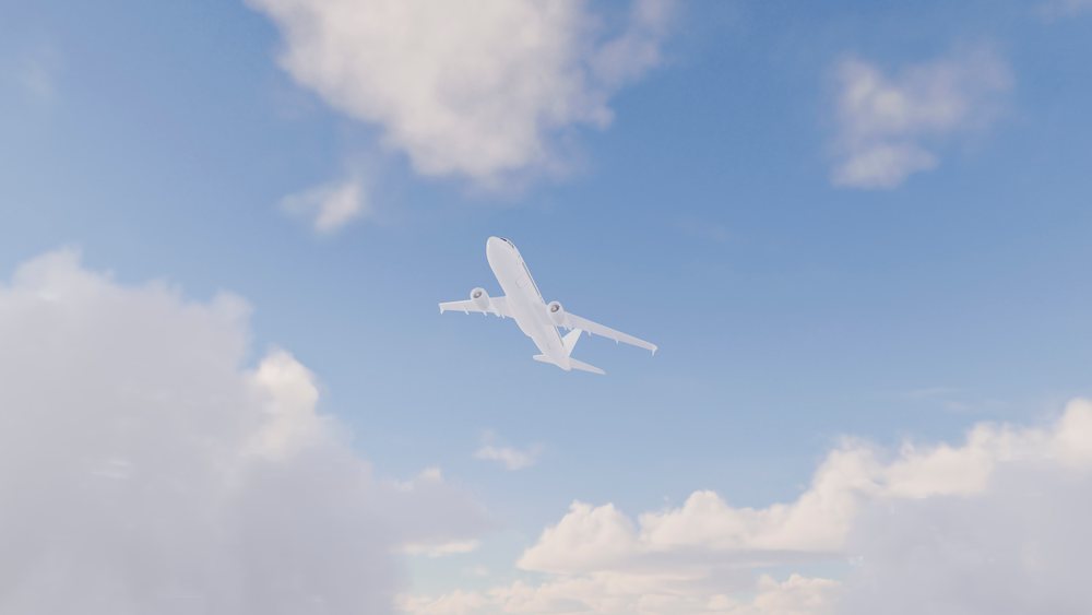 Airplane flying upward through a partly cloudy blue sky during the day.
