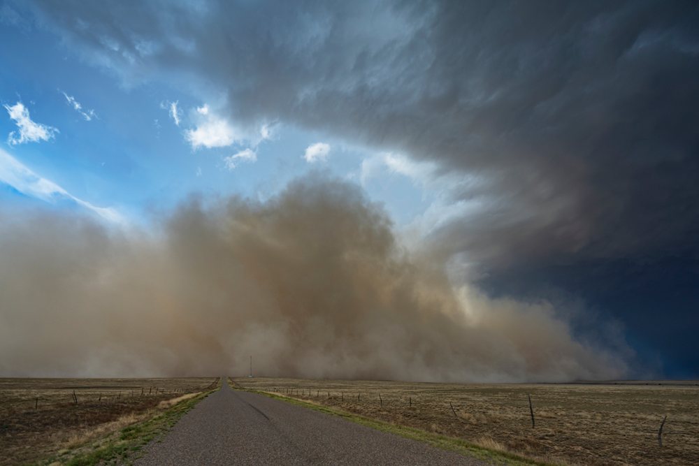 Approaching Haboob Dust Storm approaches over dry flat terrain along a rural paved road, Storm Chasing, Weather, Environment, Fowler, Colorado, USA.