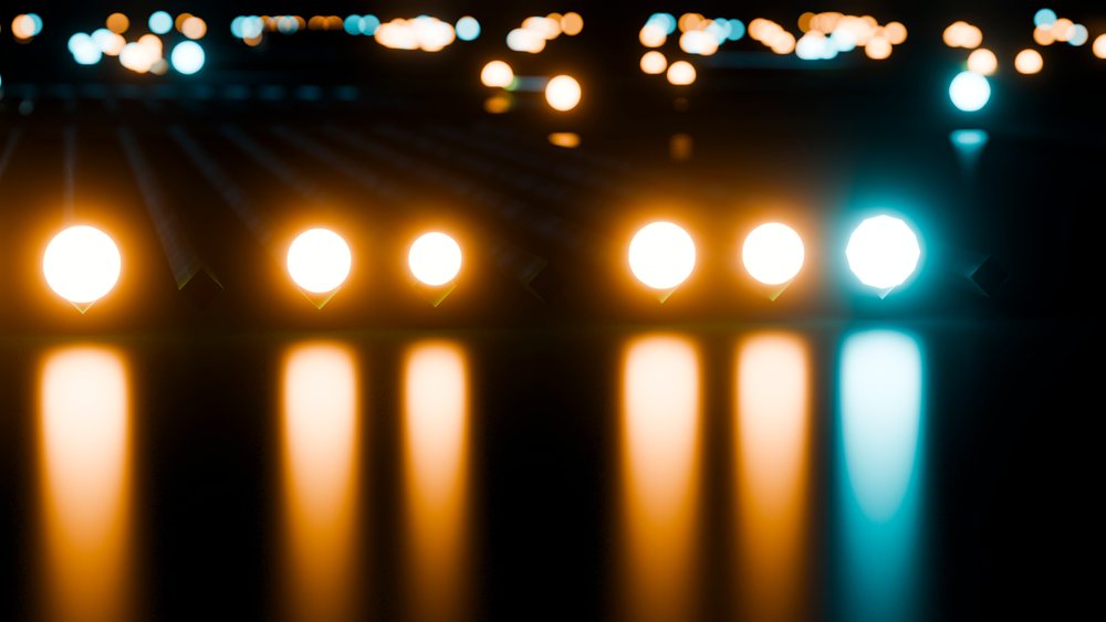 Multiple glowing light bulbs arranged in a row with reflections on a shiny dark surface in a studio setting.
