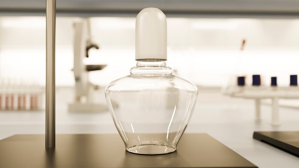 Empty glass laboratory bottle with white cap sits on a lab bench amid scientific research equipment.