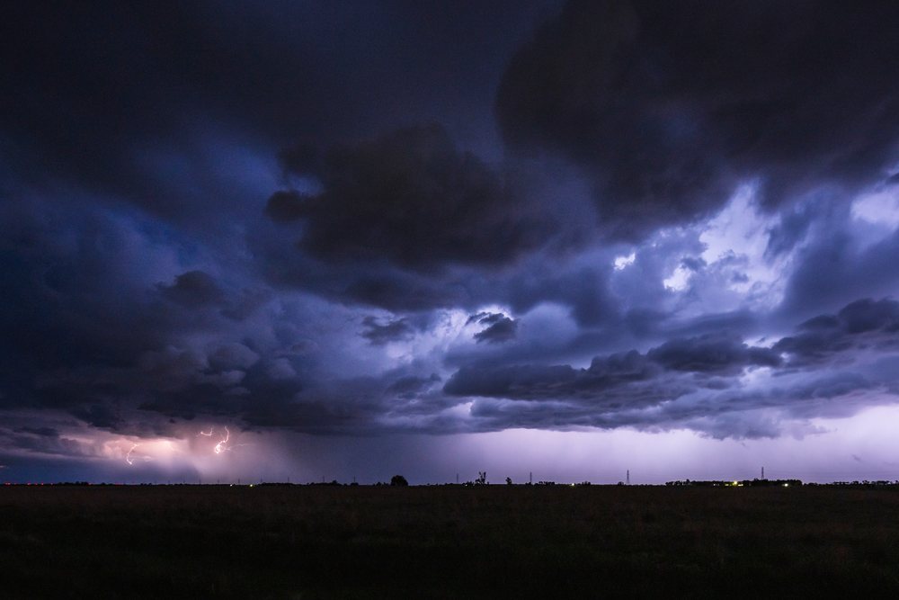 Lightning from storm clouds illuminates the dark night sky over a rural landscape, Storm Chasing, Weather, Environmental, Mitchell, South Dakota, USA.