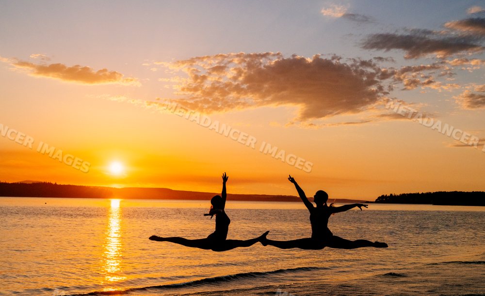 Two white people performing yoga partner acrobatics leaps