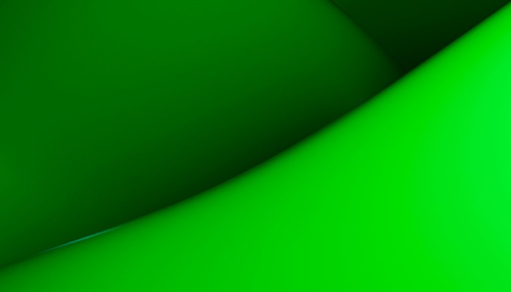 Abstract image showing smooth green curved shapes with gradient lighting creating a modern and minimal digital background.