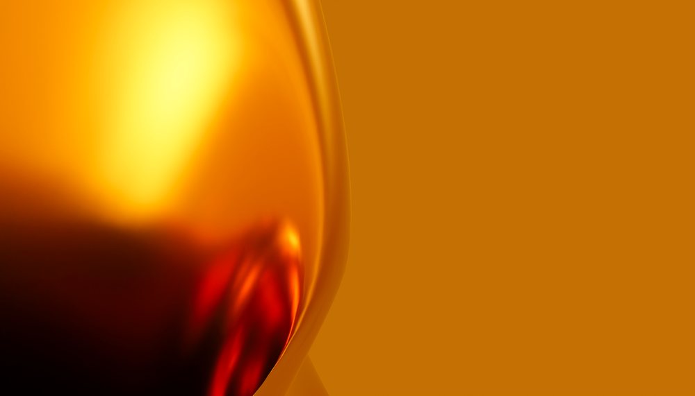 Close-up of red wine in a glass with a bright orange background.