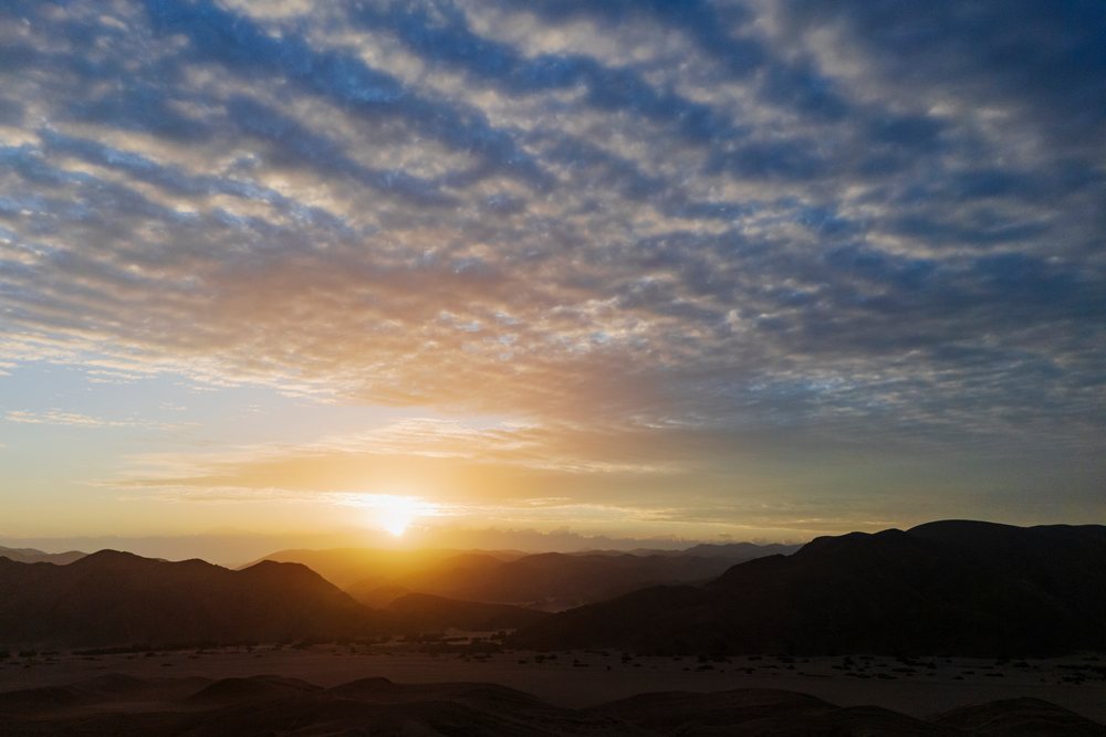 Sunrise over the mountainous Hoanib River Valley in Namibia's Kunene Region with clouds filling the sky, landscape, wildlife.