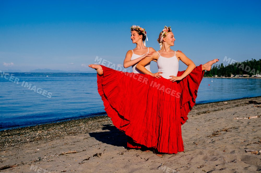 Two white women performing partner acrobatics on a beach in wa USA