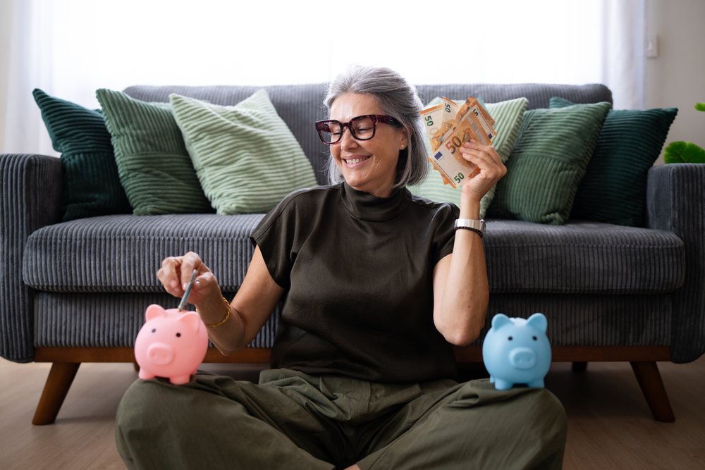 Woman saving money with piggy banks in living room, Spain.