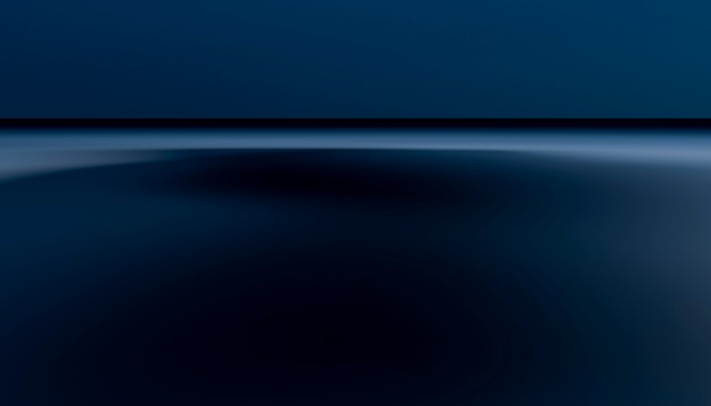 Calm ocean water at night with a clear horizon line under a dark blue sky.