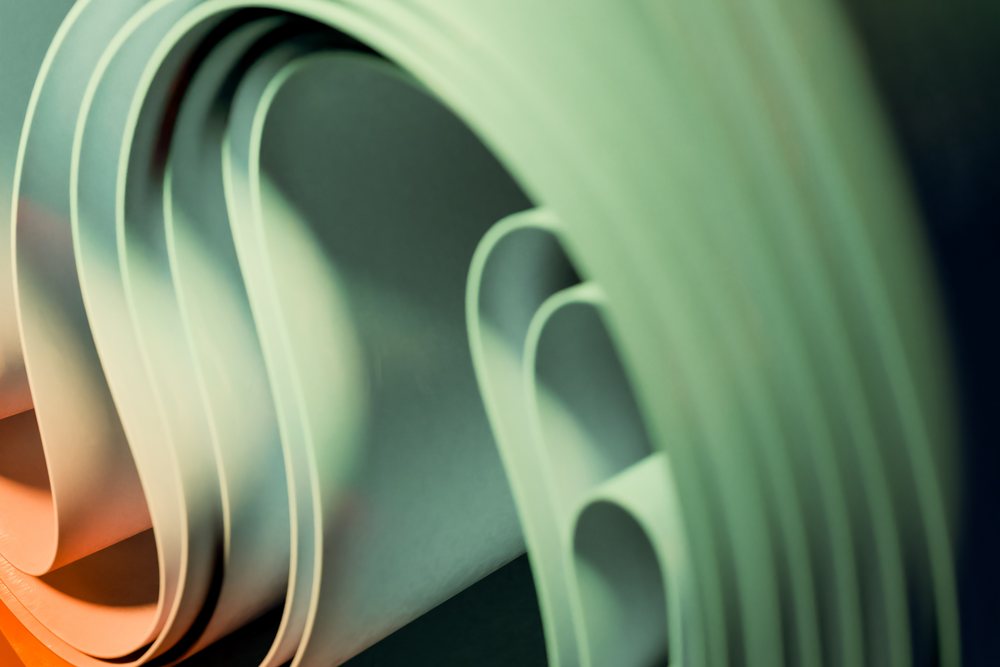 Abstract rendering of curved paper rolls with soft lighting and shadow.