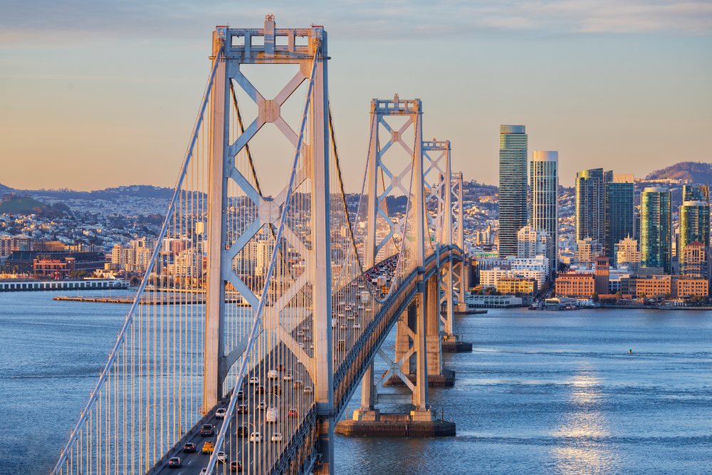Traffic flows along the San Francisco Bay Bridge at Sunrise with the city skyline across the water, Cityscapes, City Life, California, USA.