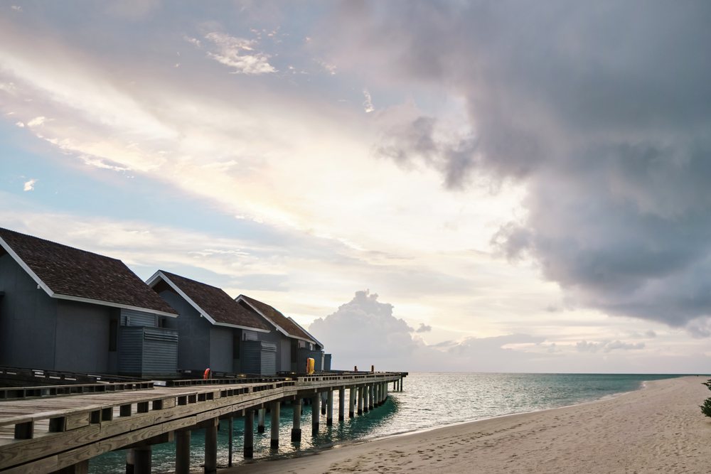 Overwater bungalows on a wooden pier at sunset on a beach in a beach